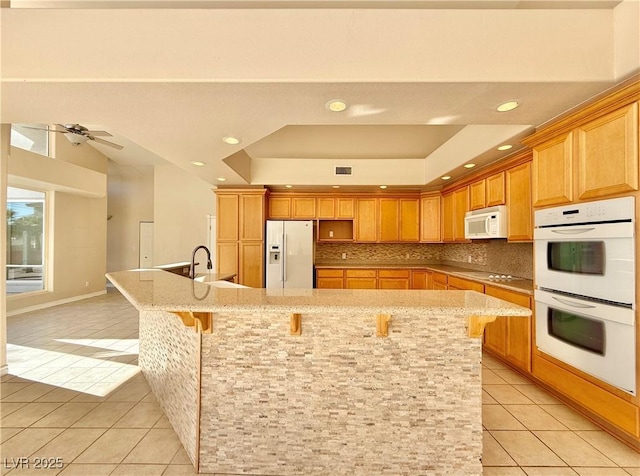 kitchen with a large island, white appliances, and light tile patterned floors