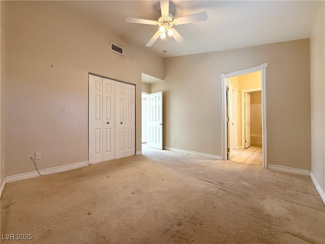 unfurnished bedroom featuring ceiling fan, a closet, light colored carpet, and lofted ceiling