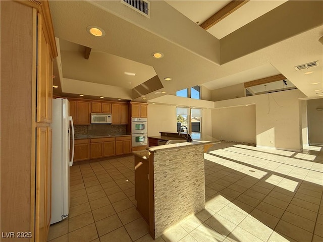 kitchen with sink, light tile patterned floors, white appliances, and backsplash