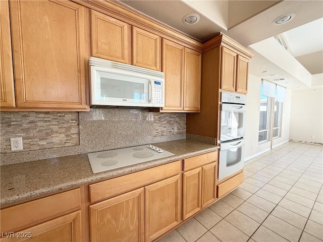 kitchen featuring tasteful backsplash, light tile patterned floors, and white appliances