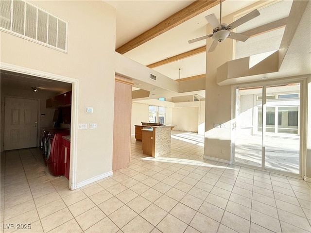 tiled spare room featuring a high ceiling, ceiling fan, separate washer and dryer, a wealth of natural light, and beam ceiling