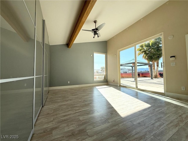 empty room featuring ceiling fan, dark hardwood / wood-style flooring, and lofted ceiling with beams