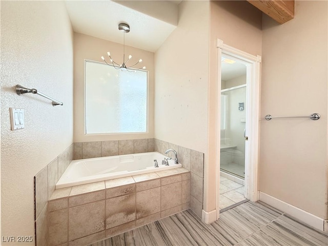 bathroom with tiled bath and a notable chandelier