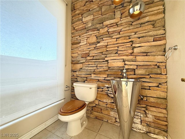 bathroom with tile patterned flooring, a healthy amount of sunlight, and toilet