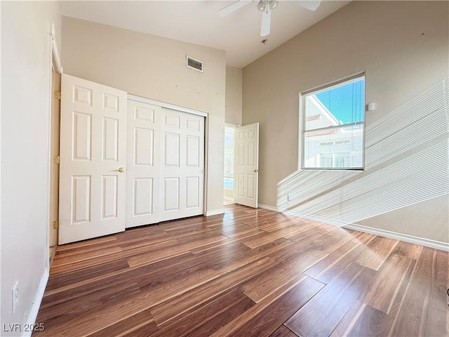 unfurnished bedroom with ceiling fan, a closet, wood-type flooring, and vaulted ceiling