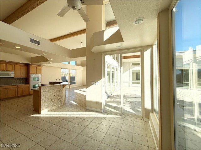 interior space with ceiling fan and beamed ceiling