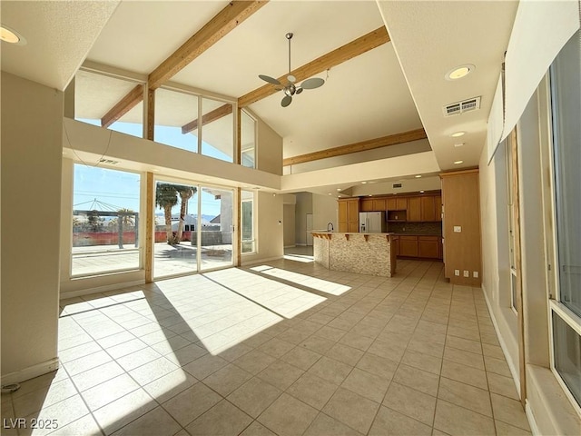 unfurnished living room featuring ceiling fan, light tile patterned floors, and lofted ceiling with beams