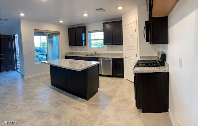 kitchen with light stone countertops, a healthy amount of sunlight, a kitchen island, and stainless steel dishwasher