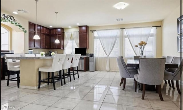 kitchen featuring light tile patterned flooring, hanging light fixtures, and a breakfast bar area