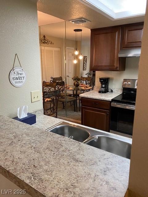 kitchen with sink, hanging light fixtures, electric range, and kitchen peninsula