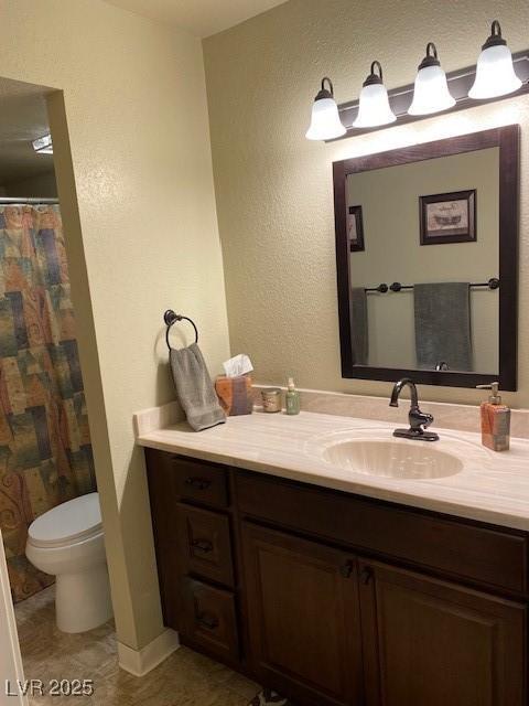 bathroom with vanity, toilet, and a textured wall