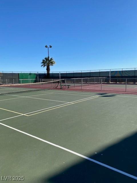 view of tennis court with community basketball court and fence