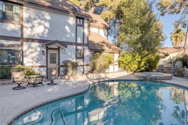 view of swimming pool featuring a patio area and an in ground hot tub