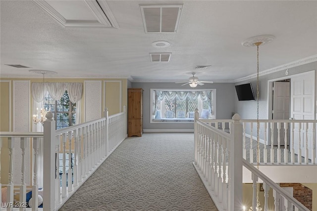 hall with plenty of natural light, ornamental molding, a chandelier, and carpet