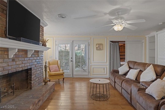 living room featuring a fireplace, ceiling fan, and light hardwood / wood-style floors