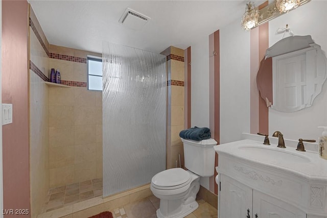 bathroom with toilet, a tile shower, vanity, and tile patterned flooring