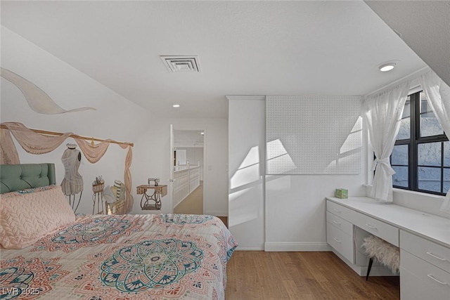 bedroom with ensuite bath and light wood-type flooring