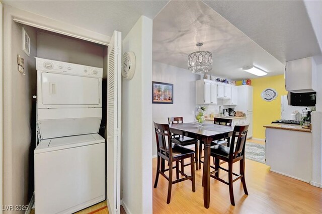 dining area featuring stacked washer and clothes dryer and light wood-type flooring