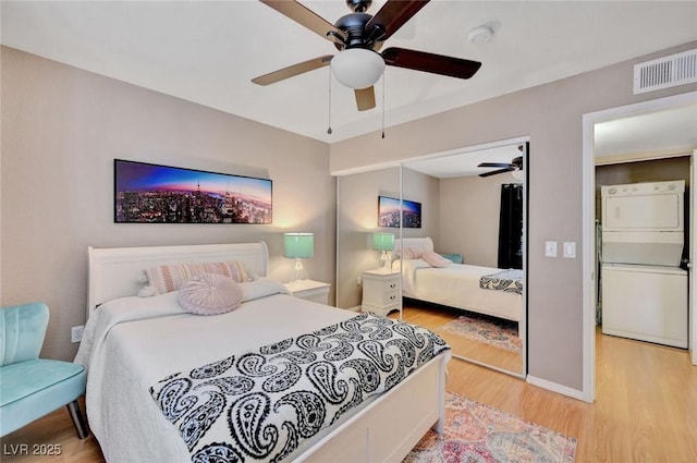 bedroom with ceiling fan, light hardwood / wood-style floors, stacked washer / dryer, and white fridge