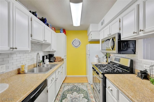 kitchen featuring light hardwood / wood-style floors, backsplash, white cabinetry, appliances with stainless steel finishes, and sink