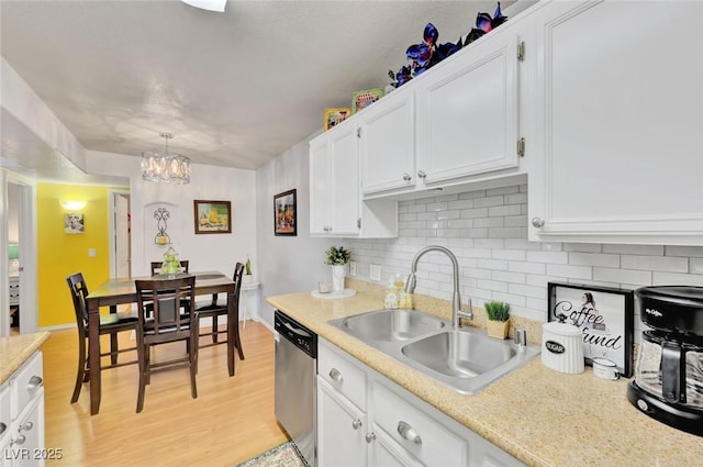 kitchen with stainless steel dishwasher, decorative light fixtures, a notable chandelier, white cabinets, and sink