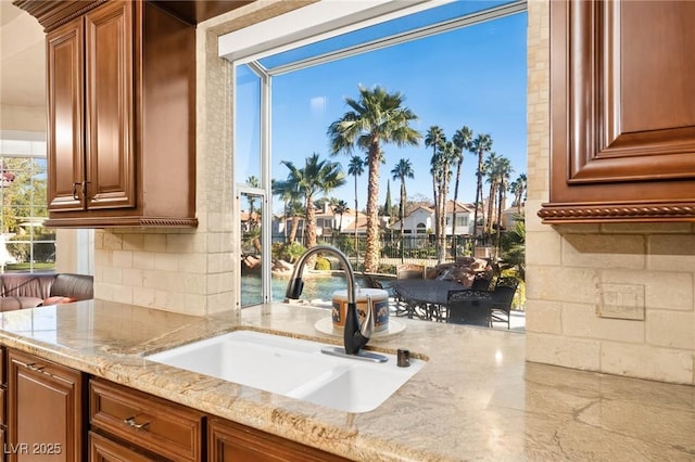 kitchen featuring backsplash, light stone counters, and sink