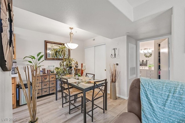 dining space with a textured ceiling and light hardwood / wood-style floors