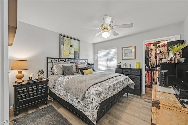 bedroom featuring light hardwood / wood-style floors, a spacious closet, a closet, and ceiling fan