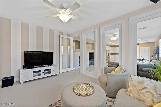 carpeted living room with ceiling fan and french doors