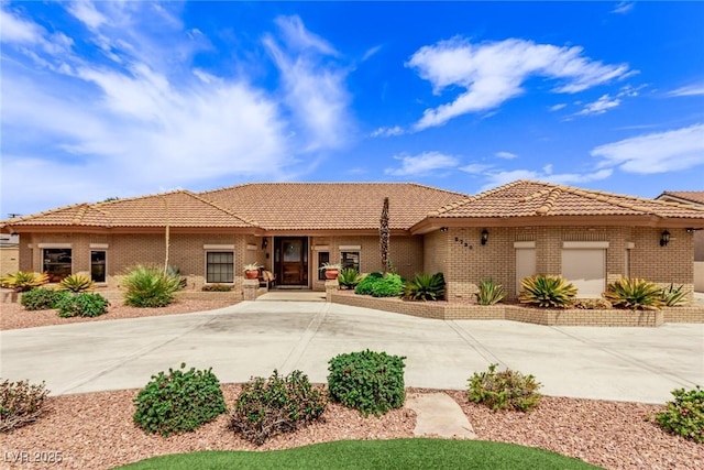 view of front of house featuring concrete driveway, brick siding, and a tiled roof