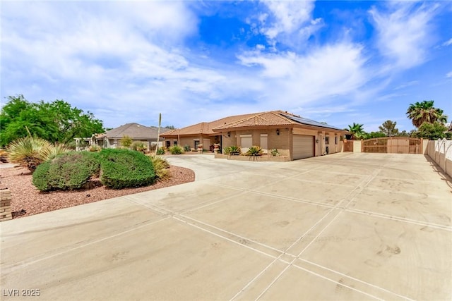 view of front of property featuring a garage, fence, driveway, a gate, and roof mounted solar panels