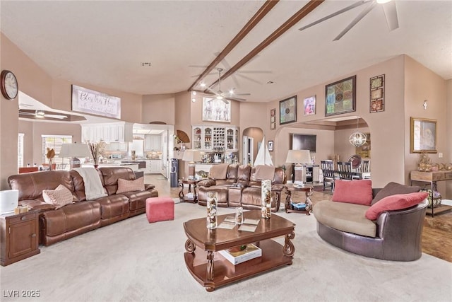 carpeted living room with beamed ceiling, a towering ceiling, and ceiling fan