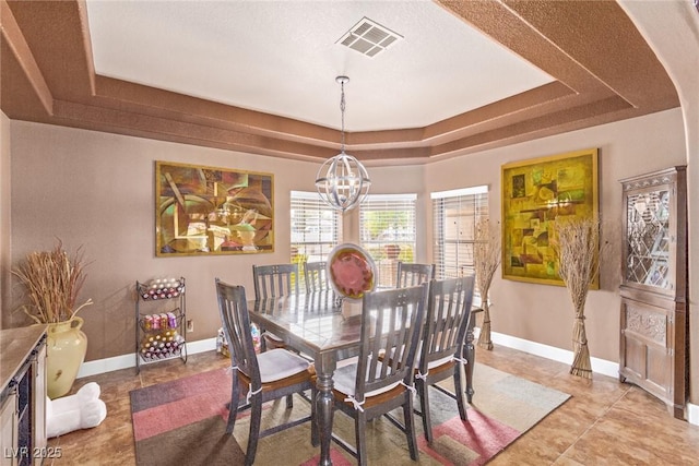 dining space featuring a tray ceiling, light tile patterned floors, and a notable chandelier