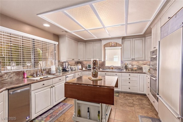 kitchen featuring backsplash, a wealth of natural light, sink, and appliances with stainless steel finishes