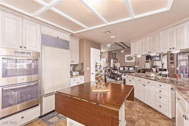 kitchen with white cabinets, paneled refrigerator, and double oven