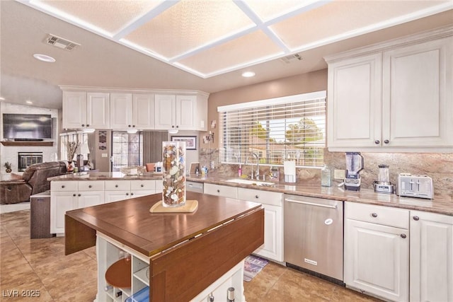 kitchen with dishwasher, a brick fireplace, visible vents, and a sink