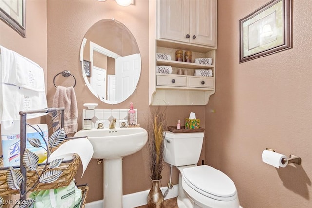 bathroom featuring baseboards, a sink, and toilet