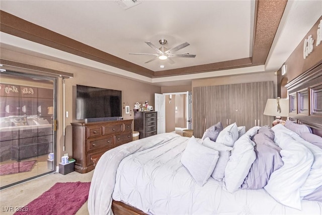 bedroom featuring ceiling fan, a raised ceiling, and light colored carpet