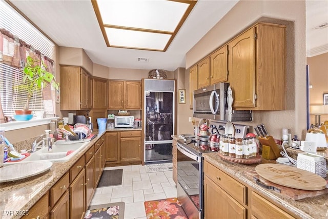 kitchen with light stone counters, light tile patterned floors, sink, and appliances with stainless steel finishes