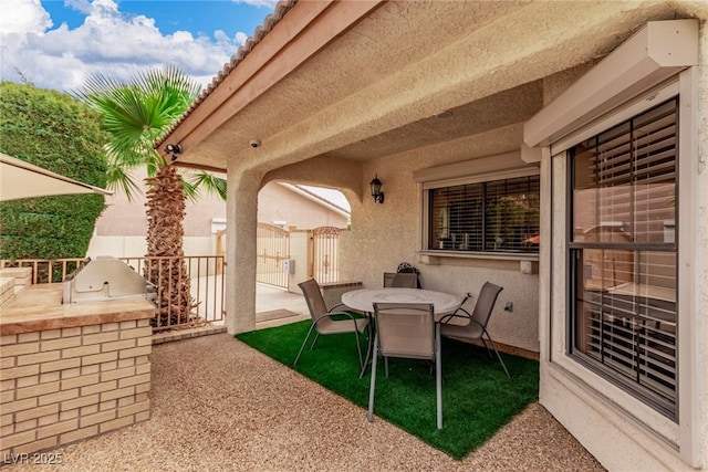 view of patio with exterior kitchen, outdoor dining area, and fence