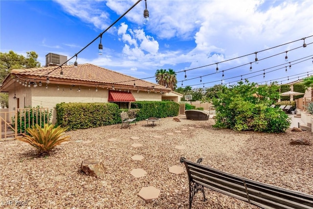 view of yard with an outdoor fire pit, fence, and central AC unit