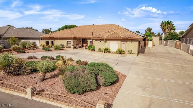 view of front of house featuring concrete driveway, a tile roof, and fence