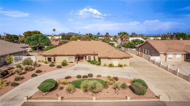 mediterranean / spanish-style house with driveway, fence, and stucco siding