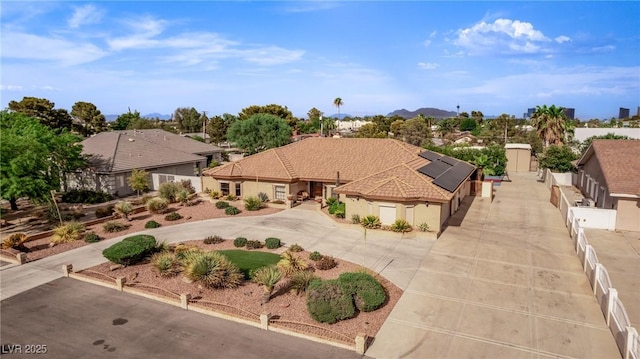 view of front of home with solar panels, fence, and concrete driveway