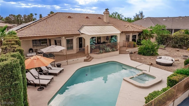 rear view of property with a pool with connected hot tub, a patio area, a tiled roof, and stucco siding