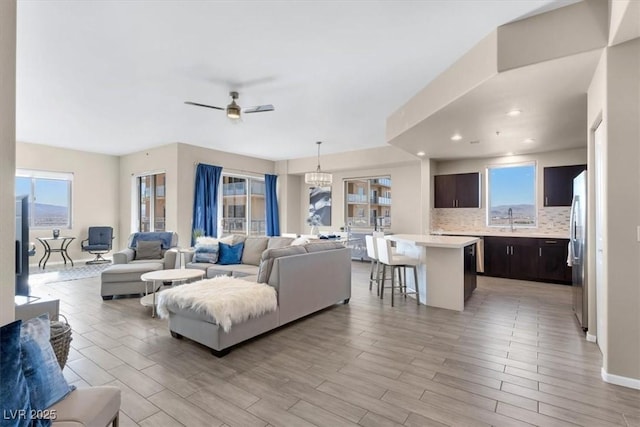 living room featuring sink, ceiling fan with notable chandelier, and light hardwood / wood-style floors