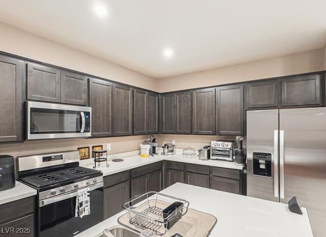 kitchen with dark brown cabinetry and appliances with stainless steel finishes