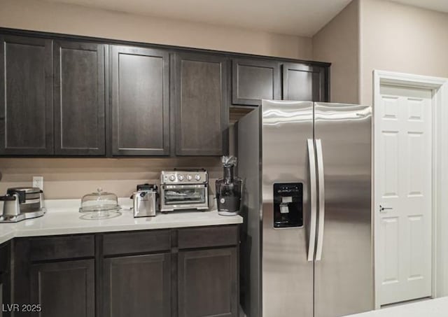 kitchen featuring stainless steel refrigerator with ice dispenser and dark brown cabinetry