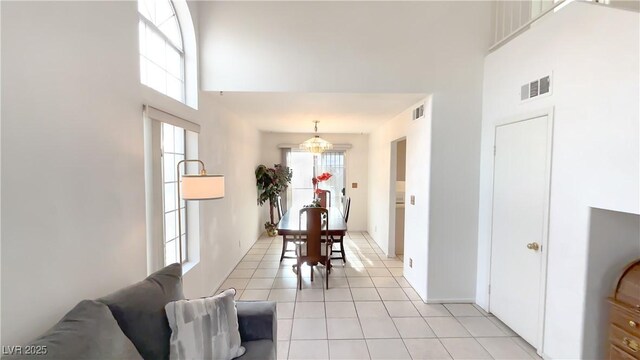 interior space with a towering ceiling, light tile patterned floors, and an inviting chandelier