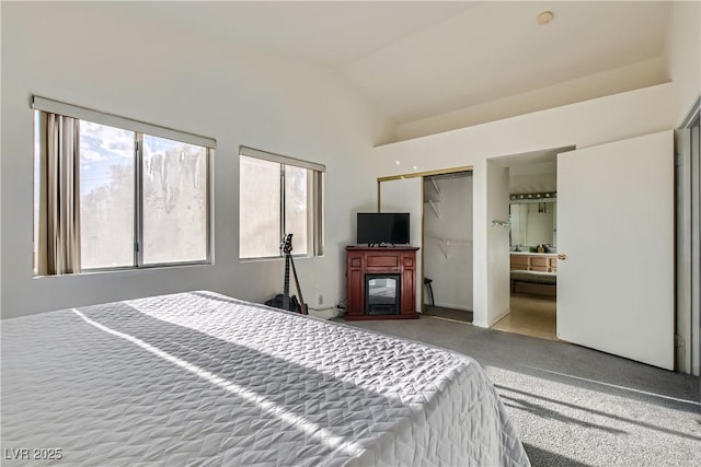 bedroom with vaulted ceiling, ensuite bathroom, and carpet flooring